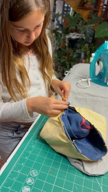 Niña concentrada alfilereando su proyecto de bolsa en el taller de Ámate