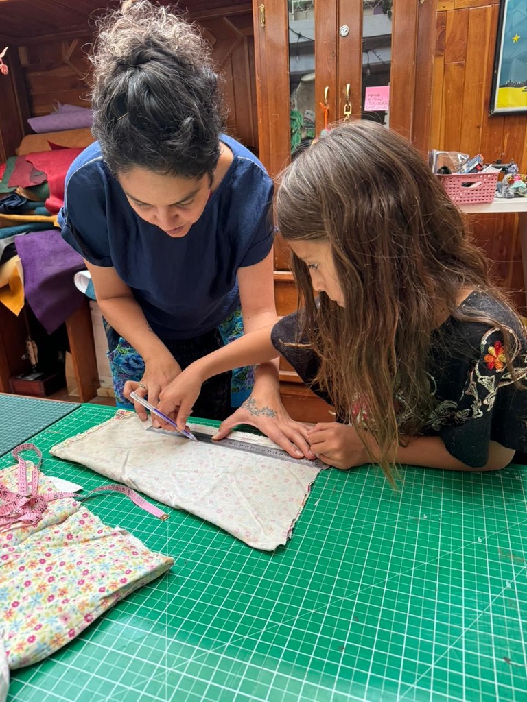Gina Vega marcando una pieza de tela junto a una alumna en el taller de Ámate