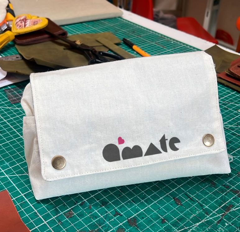 Bolso de canvas con el logo de Ámate sobre la mesa de corte del taller