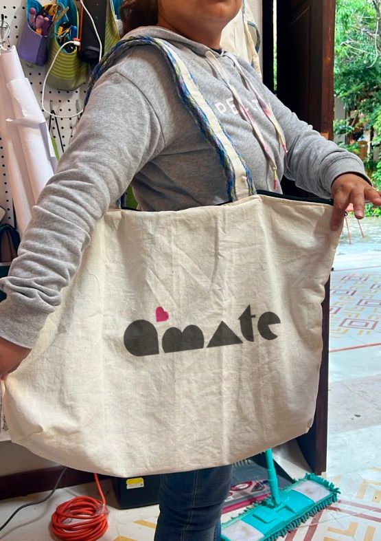 Bolsa de tela grande con el logo de Ámate, sostenida en el taller