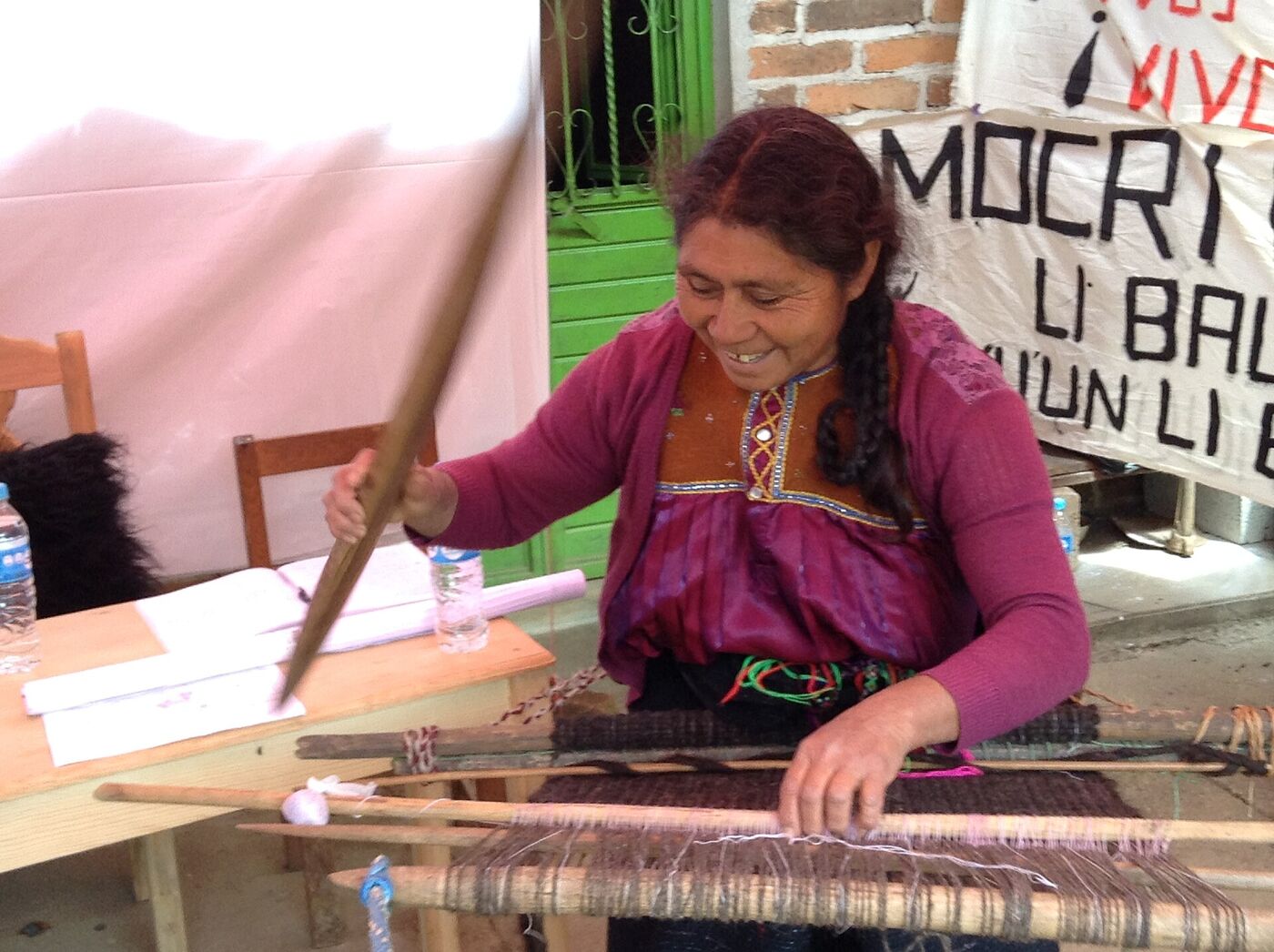 Maestra tejedora tzotzil de Chamula sonriendo mientras teje en su telar de cintura